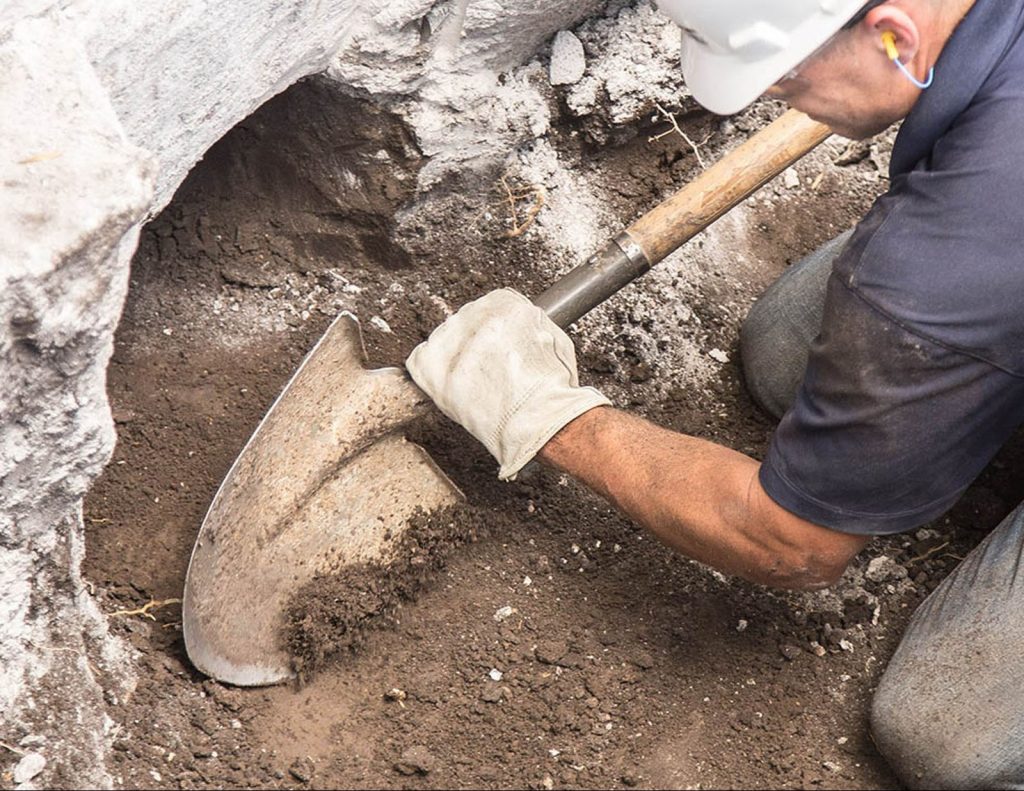 Man holding a shovel helical piers installation