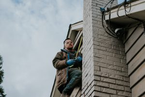 Staff near the roof holding a measuring tape