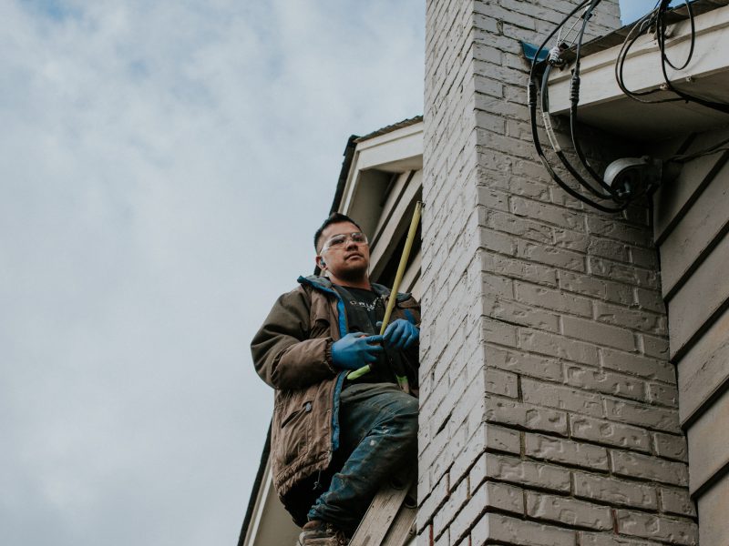 Staff near the roof holding a measuring tape