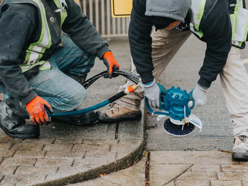 Employees assisting each other with concrete slicing