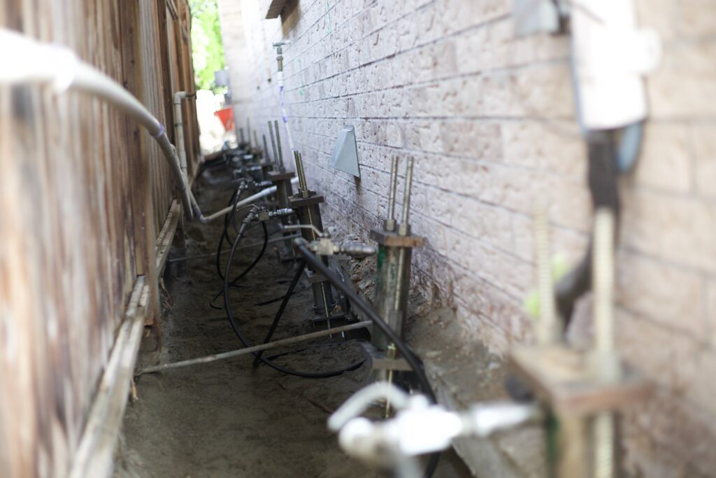 Push piers in the ground along foundation of home