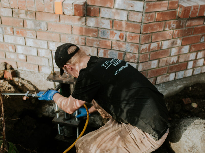 Installer fitting a pier onto the home's foundation