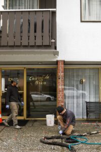 Installer injecting polylevel into the concrete in front of apartment building