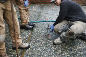 Installer injecting polylevel into the concrete in front of apartment building