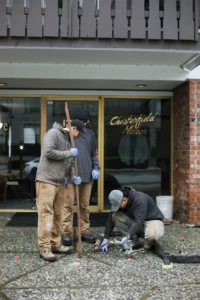 Installer injecting polylevel into the concrete in front of apartment building