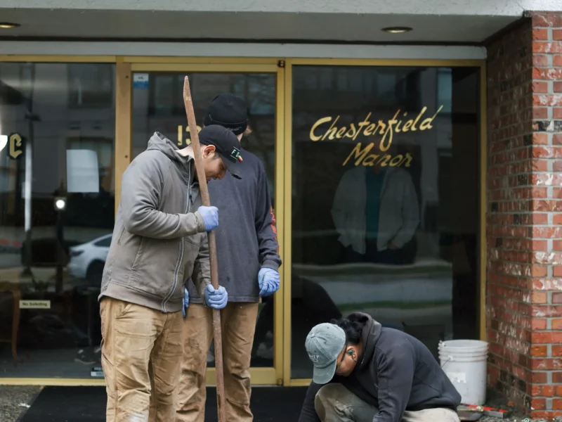 Installer injecting polylevel into the concrete in front of apartment building