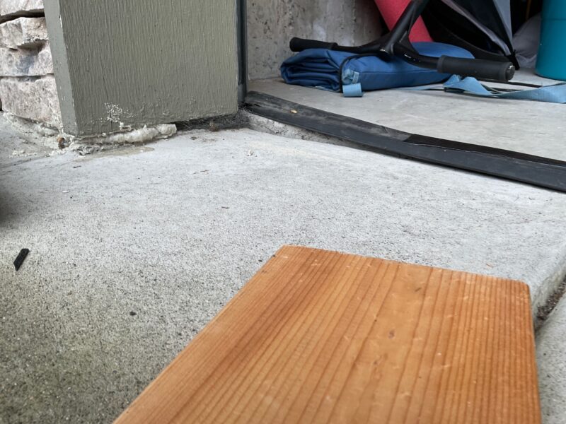 Before: Garage door lining is exposed and sunken concrete left gaps between the garage door and wall.