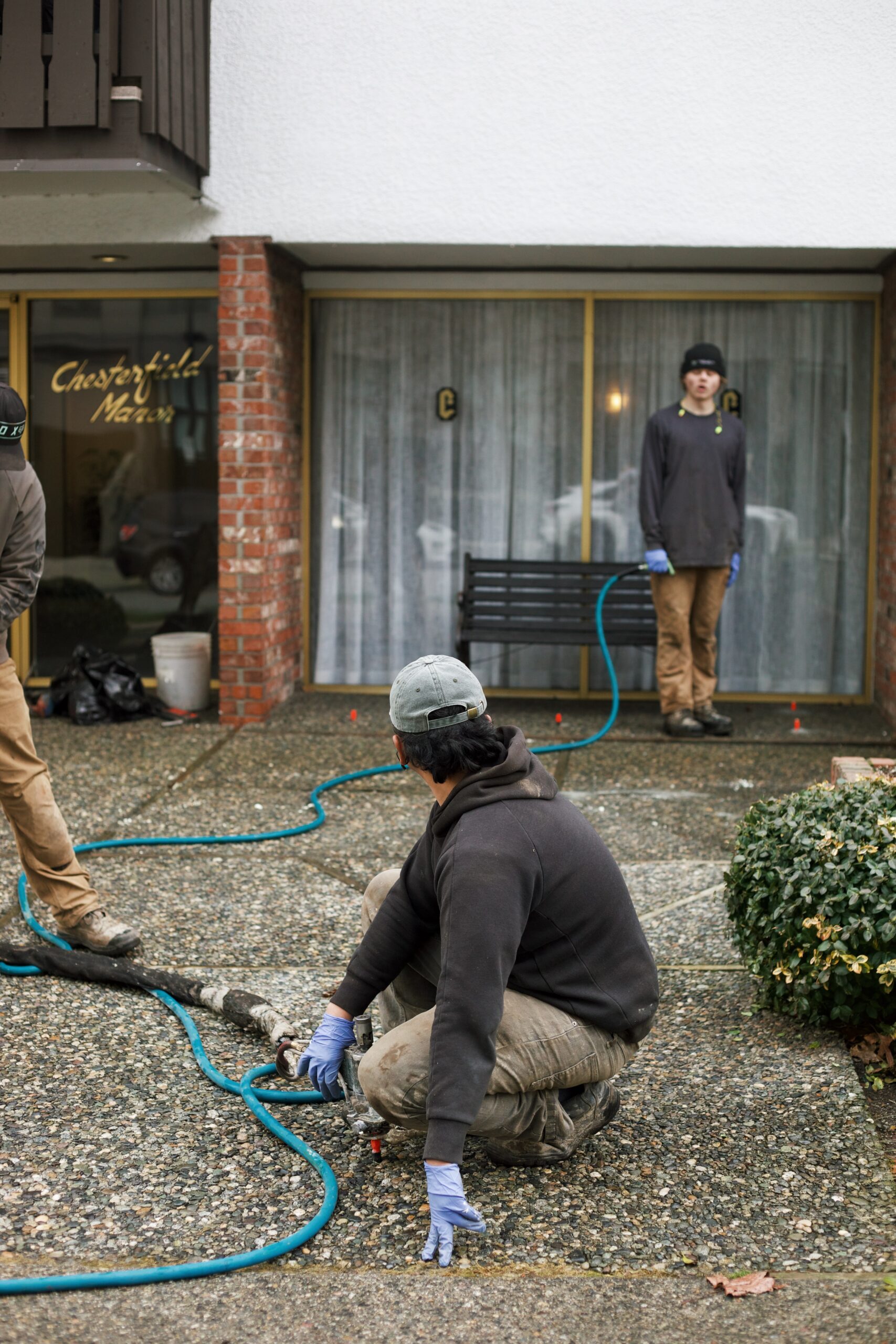 Installer injecting polylevel into the concrete in front of apartment building
