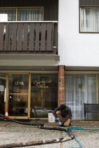 Installer injecting polylevel into the concrete in front of apartment building
