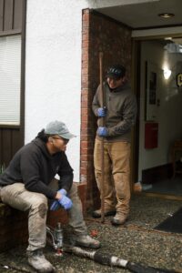 Installer injecting polylevel into the concrete in front of apartment building