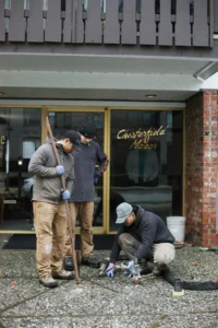 Installer injecting polylevel into the concrete in front of apartment building