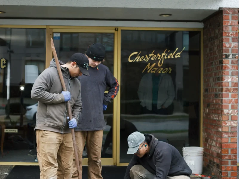 Installer injecting polylevel into the concrete in front of apartment building