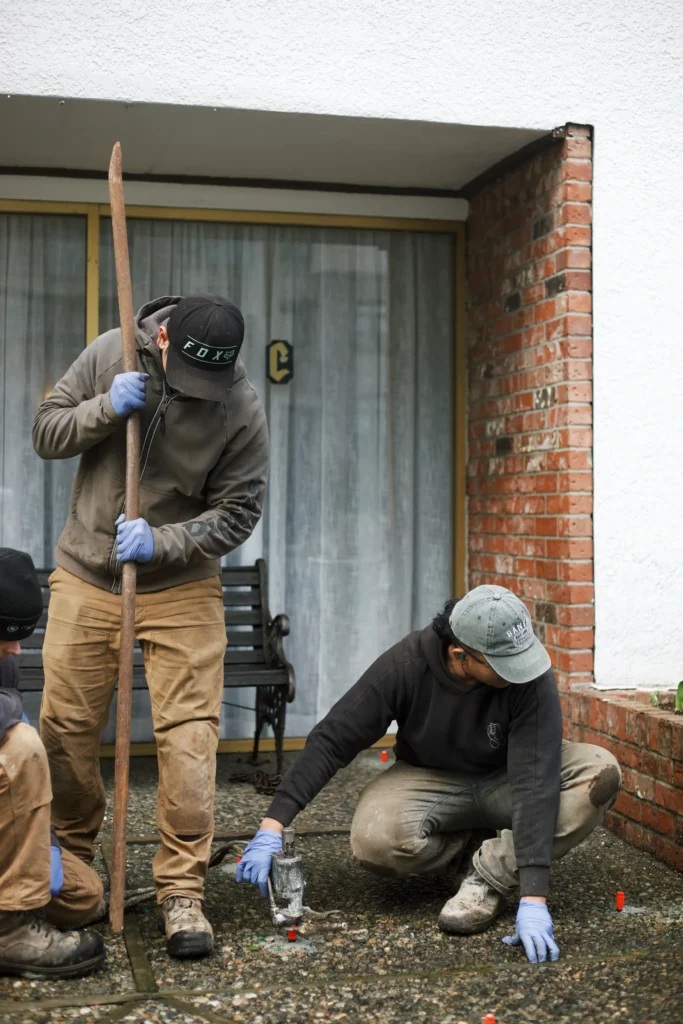 Installer injecting polylevel into the concrete in front of apartment building