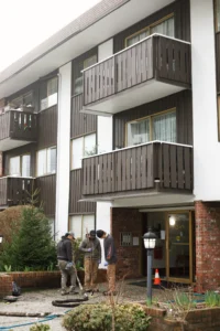 Installer injecting polylevel into the concrete in front of apartment building