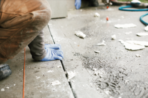 Contractor's hands in blue gloves on concrete trip hazard