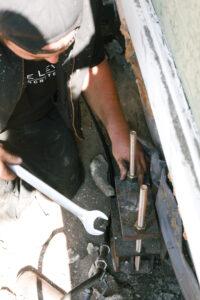 installer adjusting bracket on house foundation